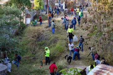 Gran grupo de ciudadanos realizando un tequio vecinal para la limpieza de maleza y mantenimiento de áreas verdes en Oaxaca de Juárez, enero 2026.